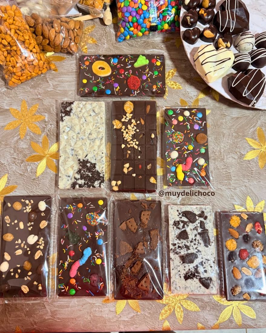 Mesa con nueve tabletas de chocolate decoradas y una bandeja de bombones